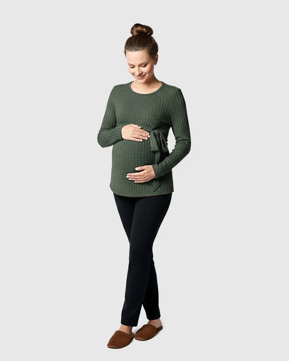 Pregnant woman in a ribbed olive green tie-waist long sleeve maternity sweater and black pants.