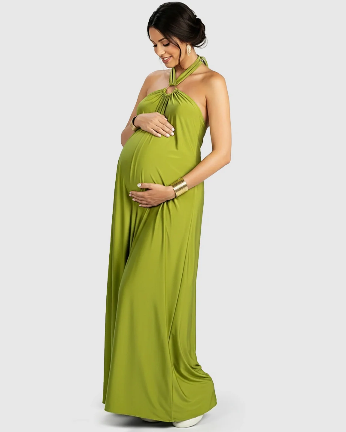 Pregnant woman in a flowing, backless lime green chiffon halter neck maxi dress with gold accents.