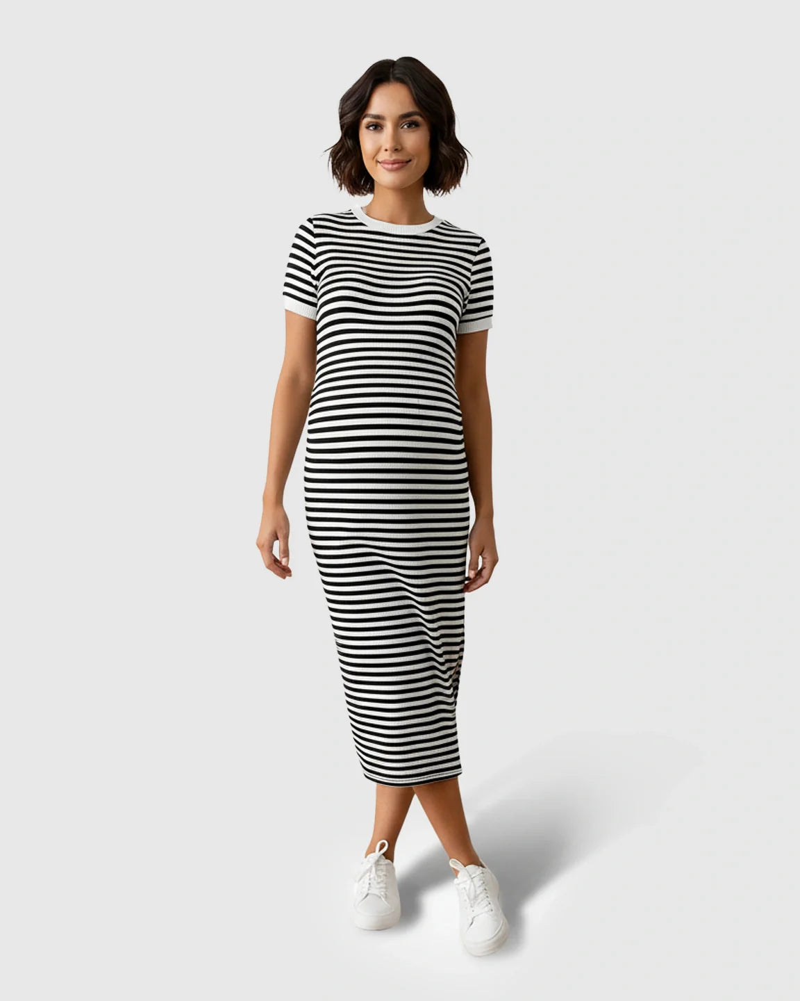 Smiling woman in a black and white striped knit maternity midi column dress with short sleeves and a side slit.