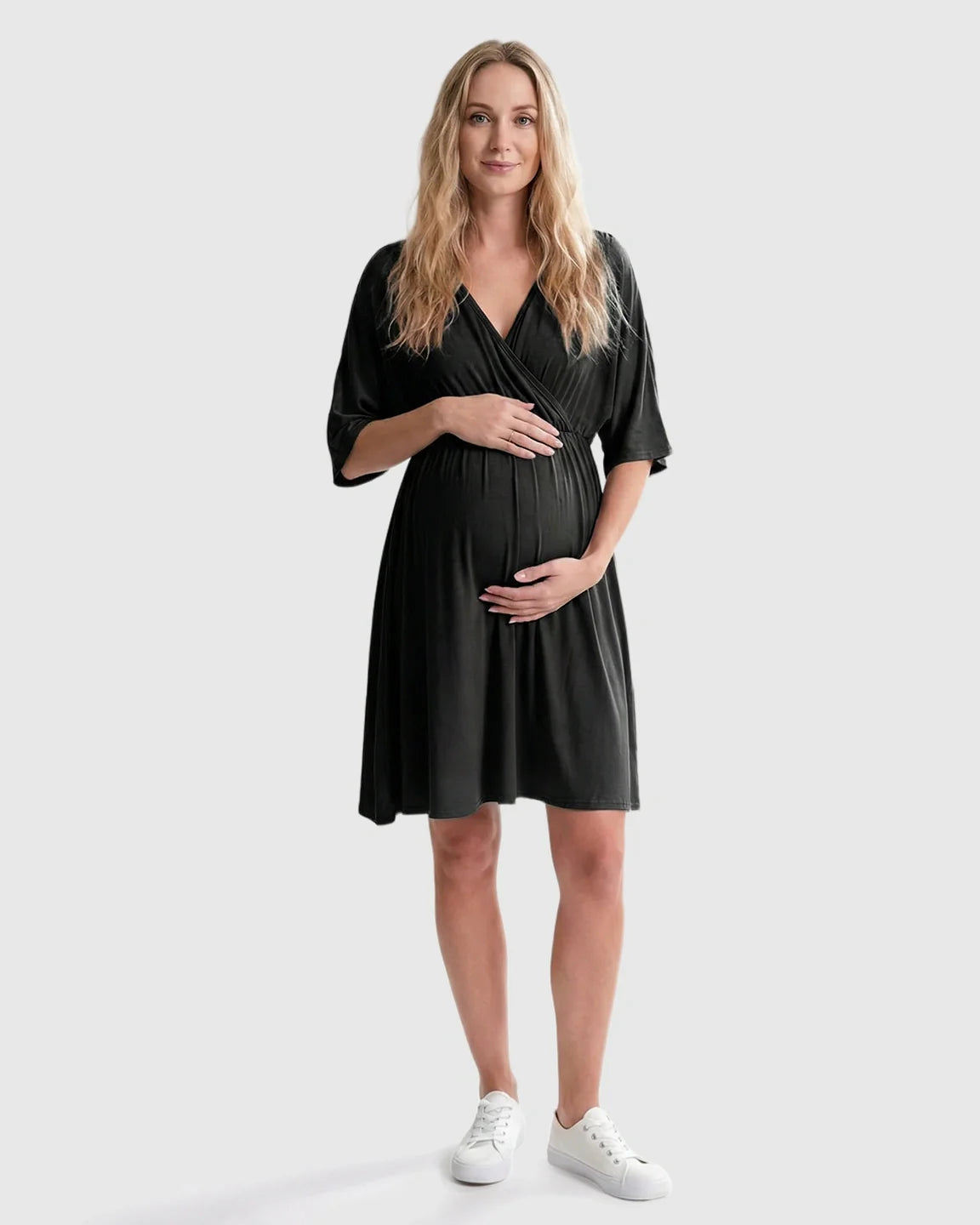 Pregnant woman in a black cross-front maternity midi dress with 3/4 sleeves, flattering her bump.