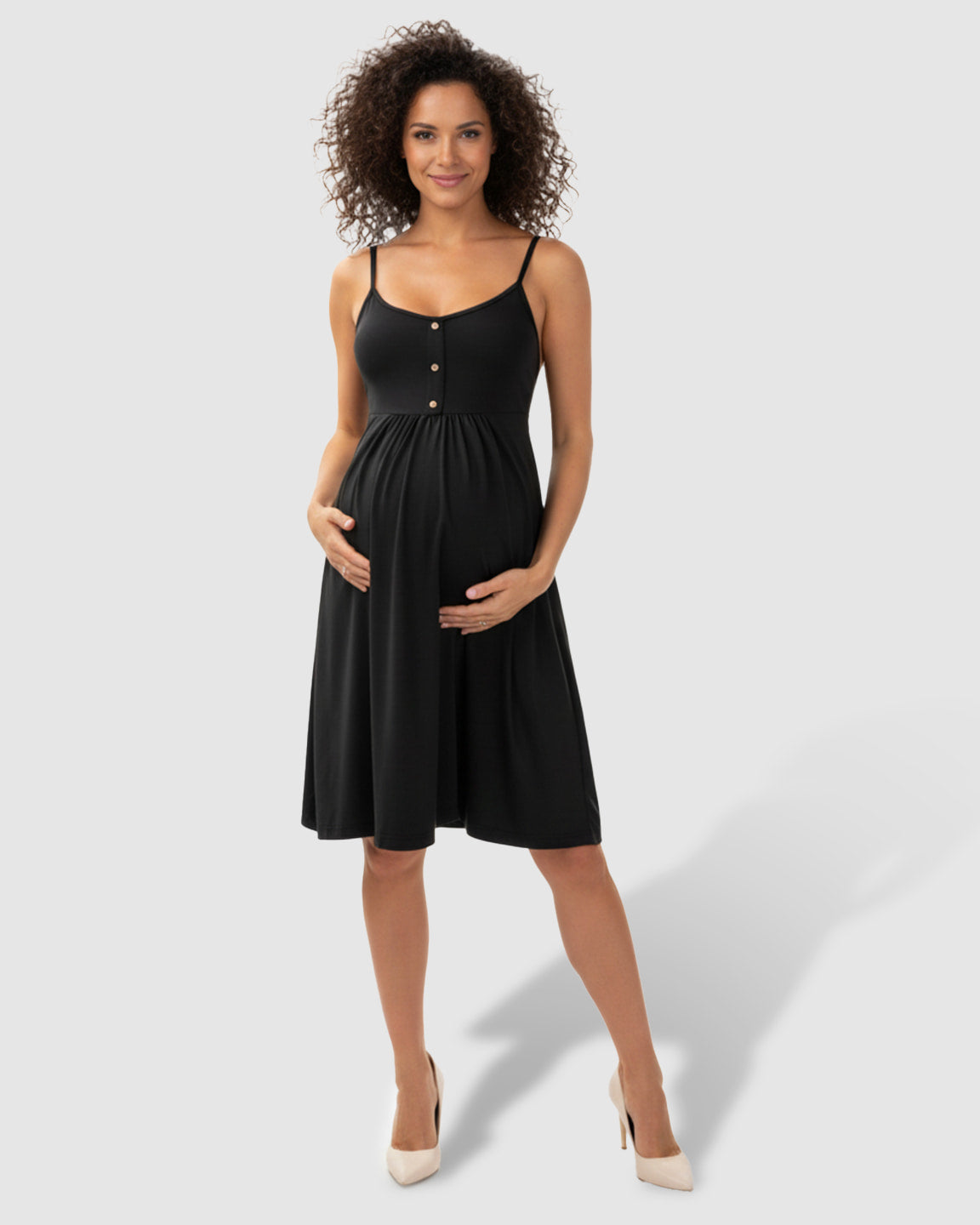 Smiling pregnant woman in a black A-line maternity midi dress with thin straps and front buttons.