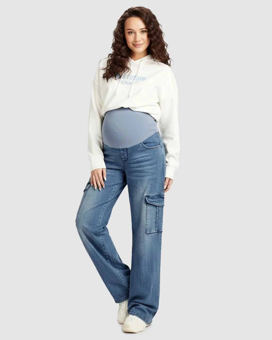 Pregnant woman smiling, wearing Bump Society high-waist wide-leg maternity cargo jeans in light wash denim with an over-bump panel.