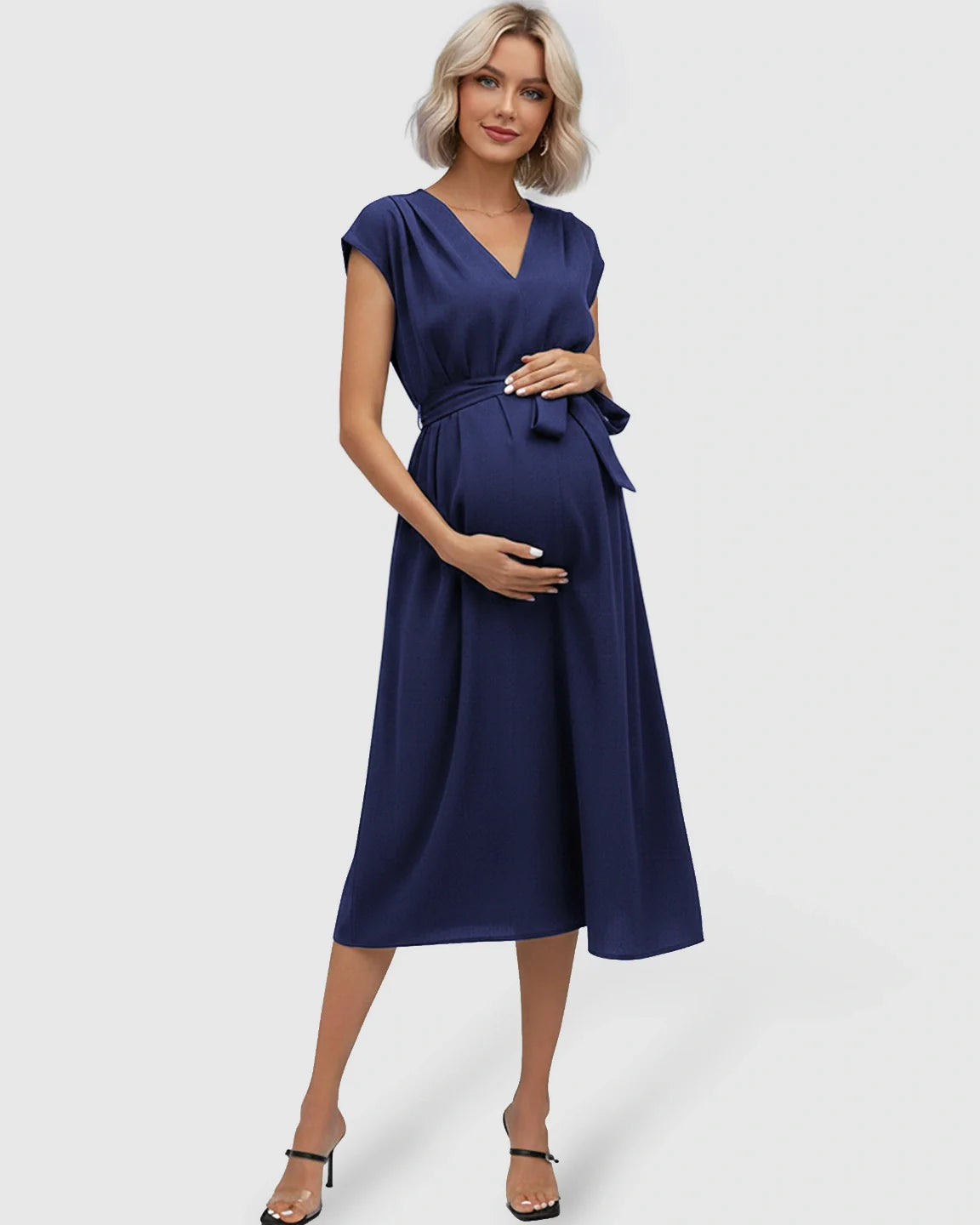 Maternity midi dress in navy blue with V-neck, flutter sleeves, and adjustable tie-waist over a baby bump.