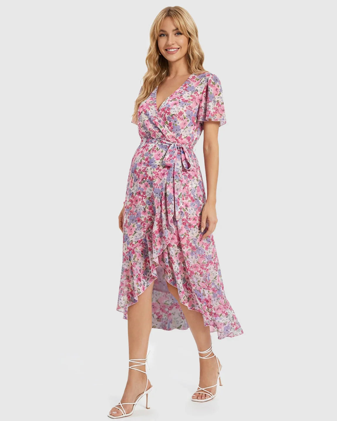 Blonde model in a pink and purple floral V-neck maternity midi dress with a ruffled high-low hem and tie waist.