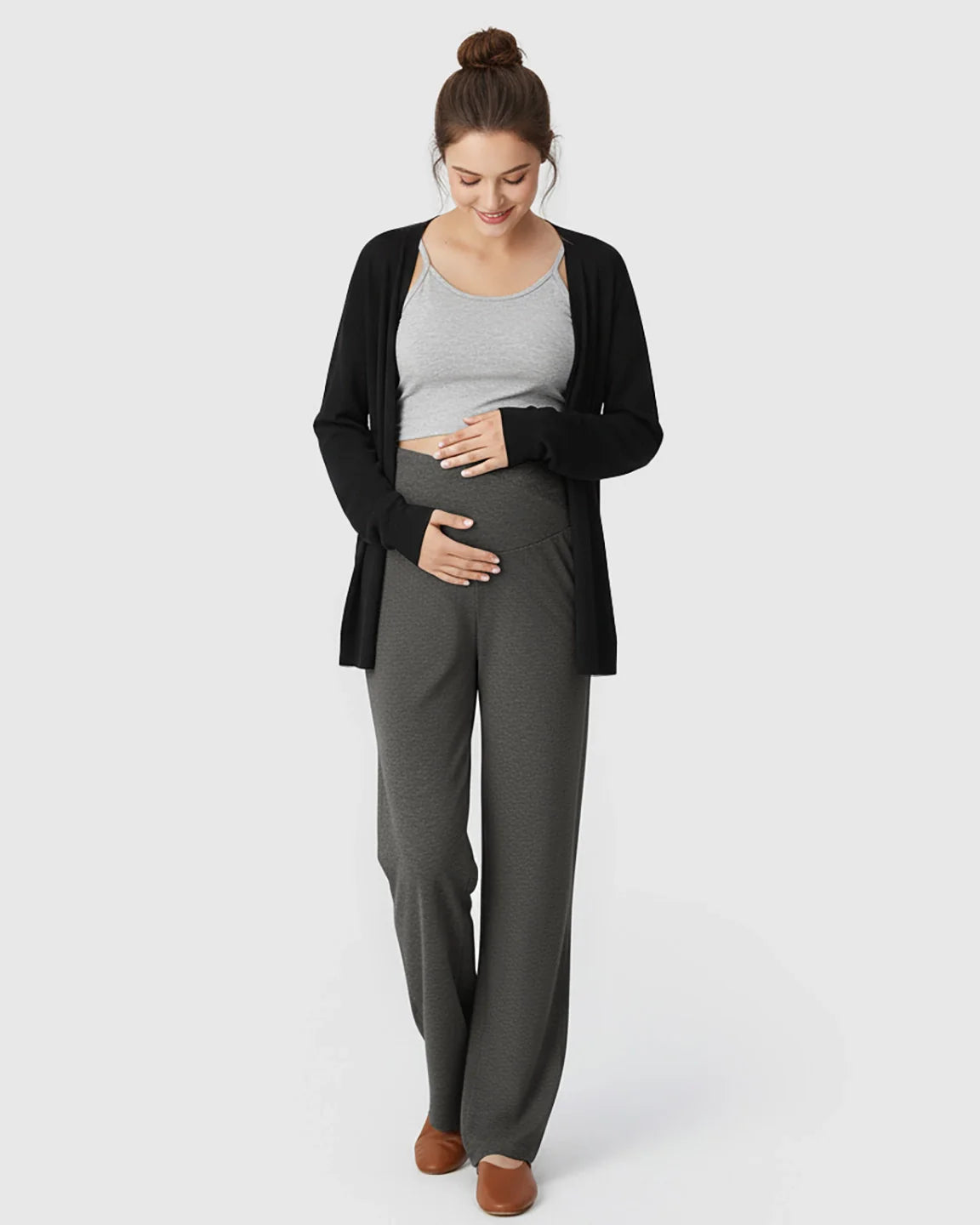 Pregnant woman in charcoal wide-leg maternity lounge pants with a crossover waist, grey tank, and black cardigan.