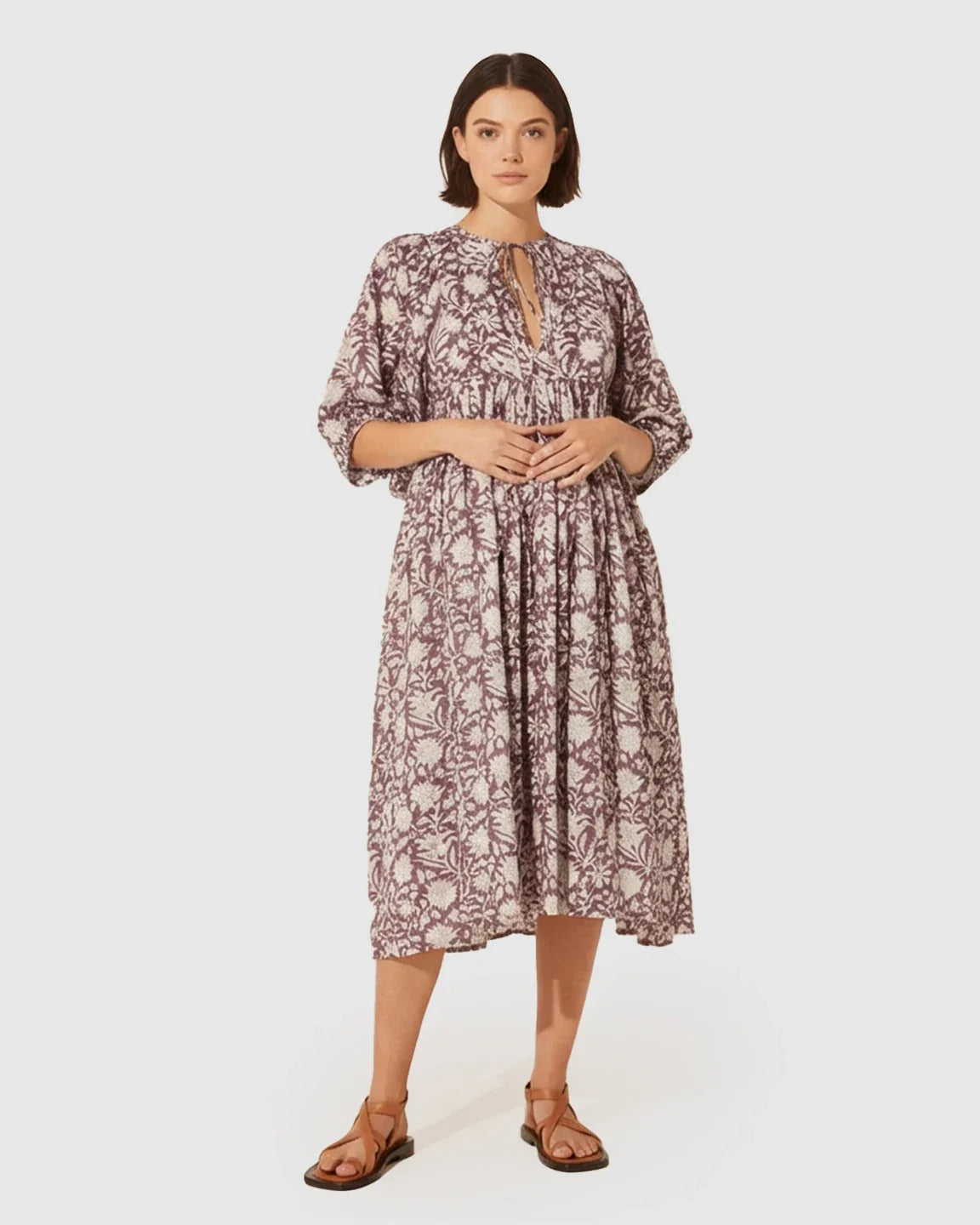 Woman in a loose-fit, gathered shoulder floral maternity midi dress with puff sleeves and brown sandals.