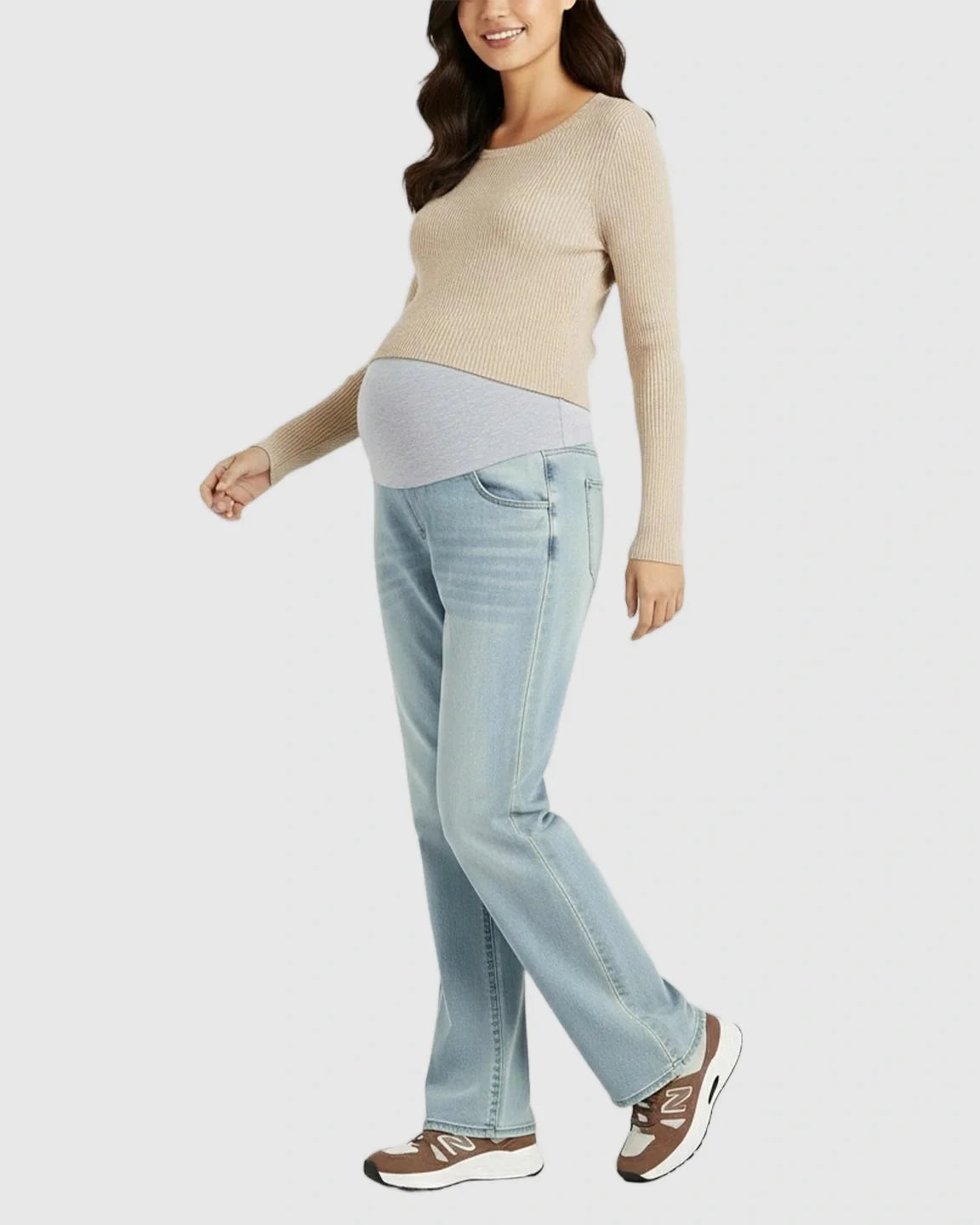 Smiling pregnant woman in light blue straight-leg maternity jeans with a grey belly band and a beige top.