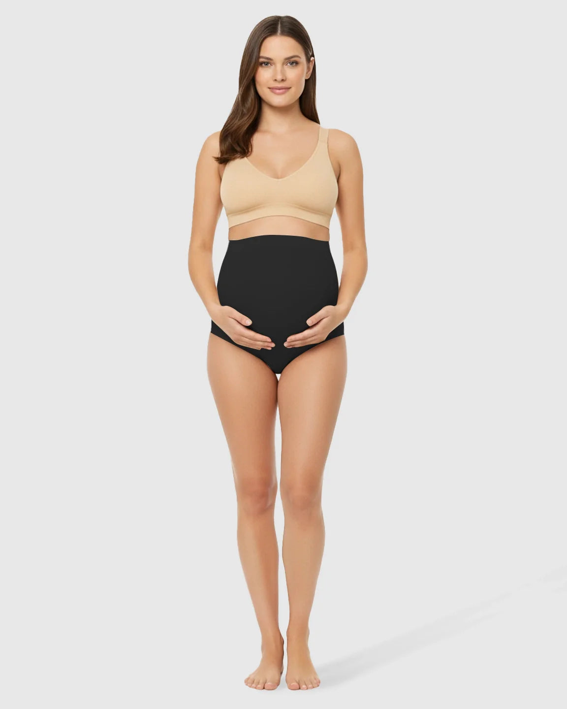Pregnant woman in black high-waist seamless belly-support maternity underwear and a nude bra.
