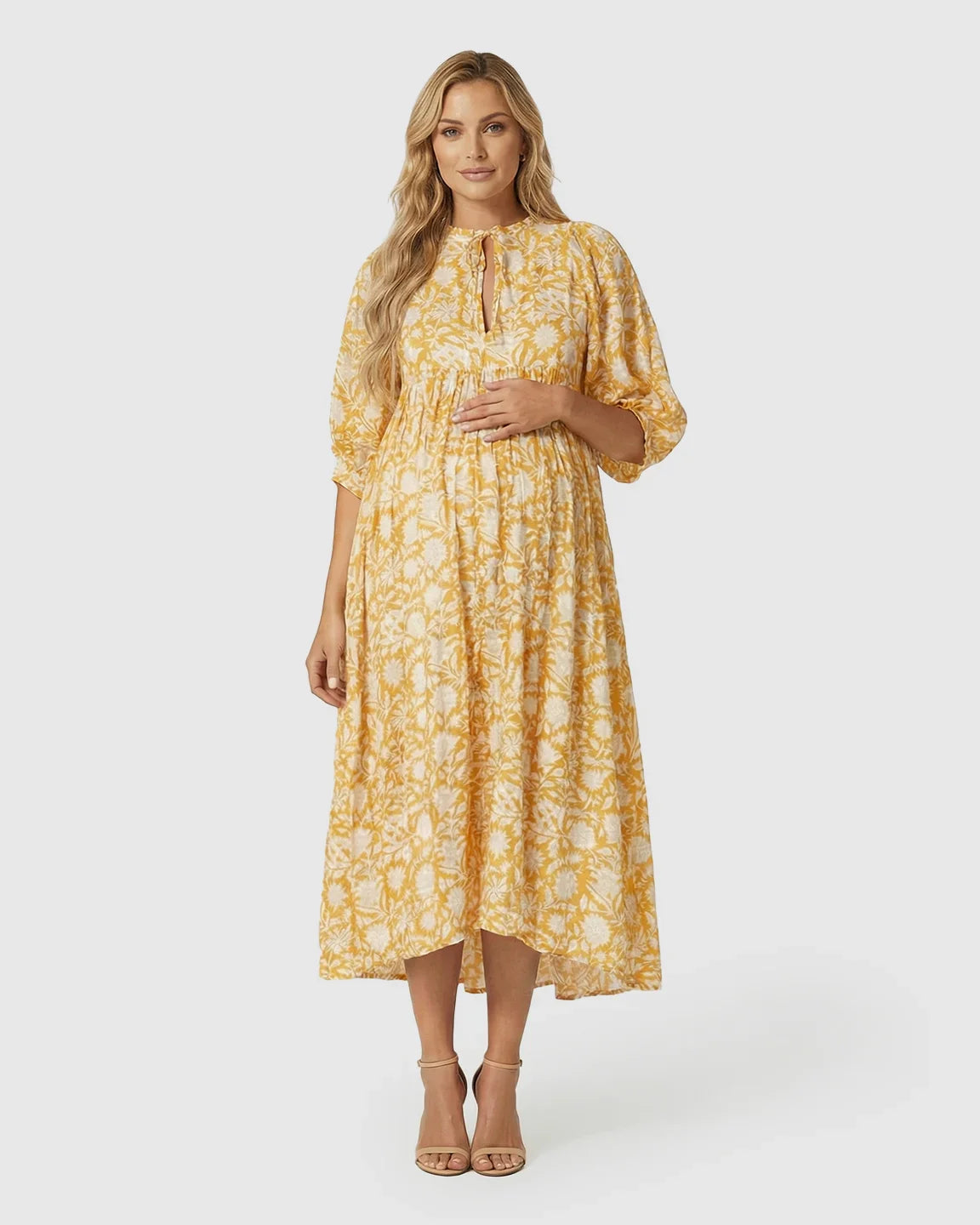 Pregnant woman in a yellow floral loose-fit maternity midi dress with gathered shoulders and puff sleeves.