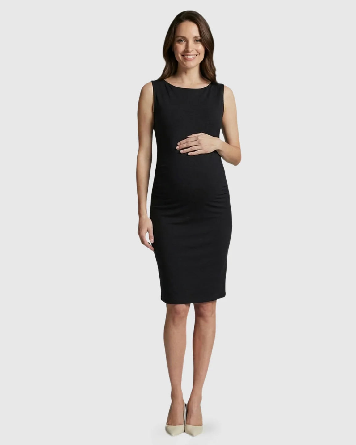 Smiling pregnant woman in a black sleeveless bodycon maternity midi dress, gently holding her belly.