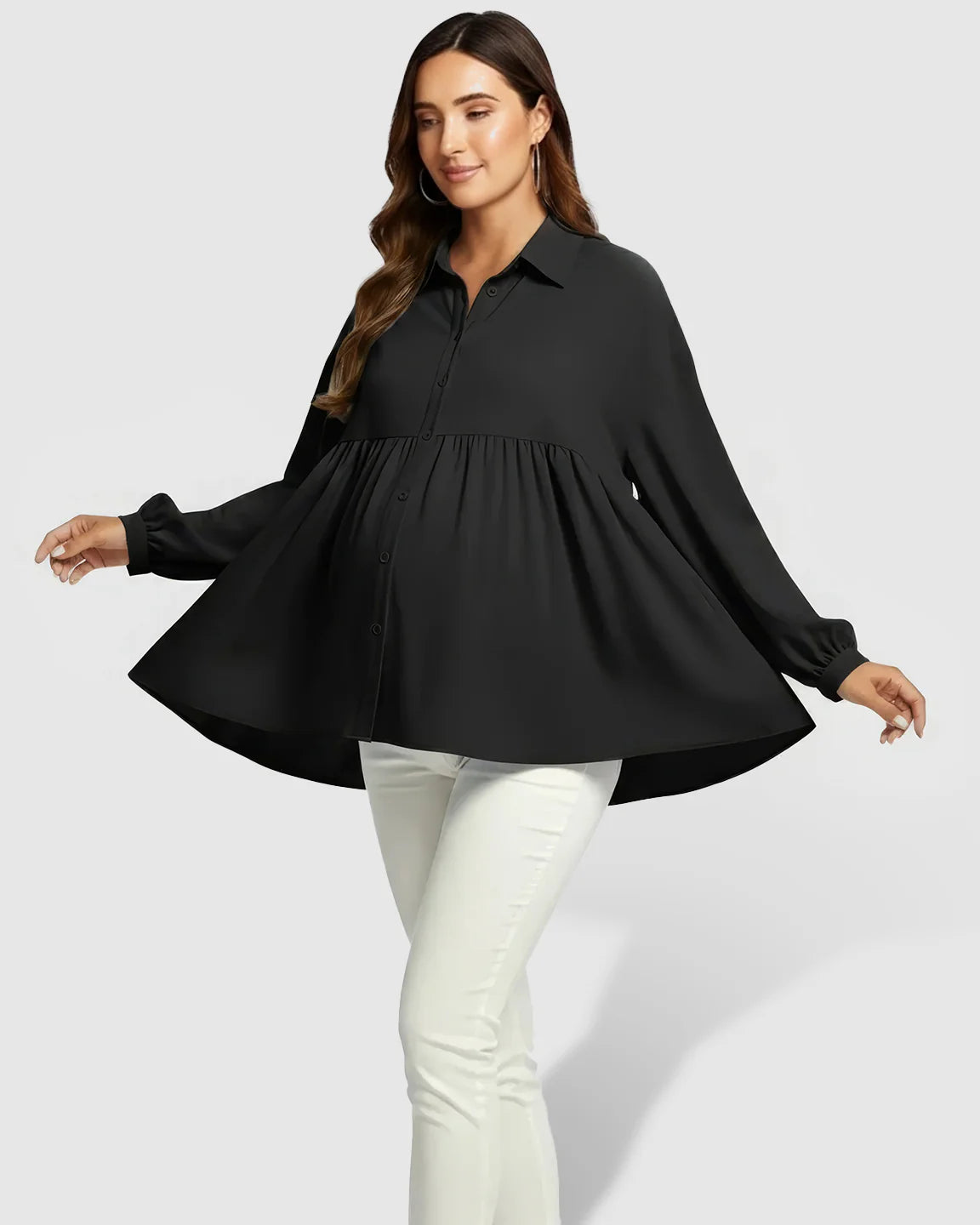 Woman in black chiffon lapel long sleeve maternity shirt with babydoll fit, paired with white pants.
