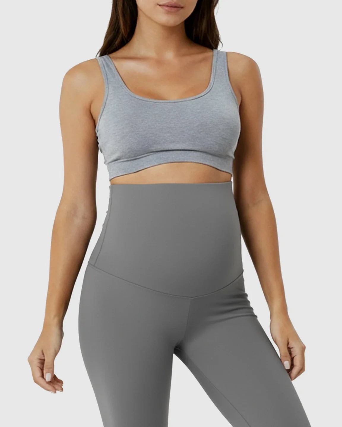 Woman wearing grey high-waist maternity support leggings and a grey sports bra, showcasing the comfortable fit.