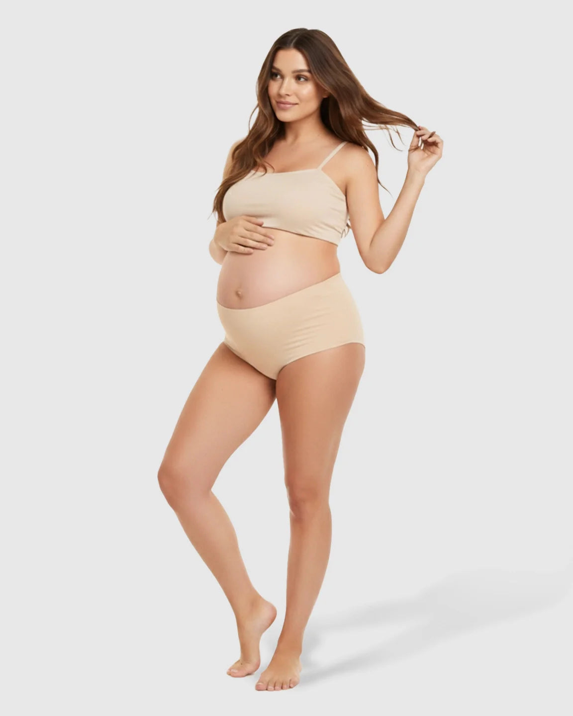 Pregnant woman in seamless nude high-waist maternity support underwear and matching bandeau top.