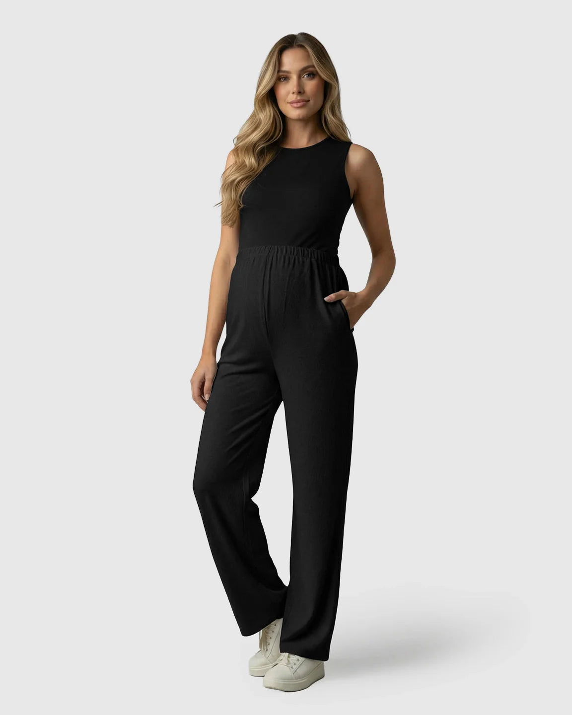 Woman wearing black elastic waist wide-leg maternity pants with a matching sleeveless top and white sneakers.