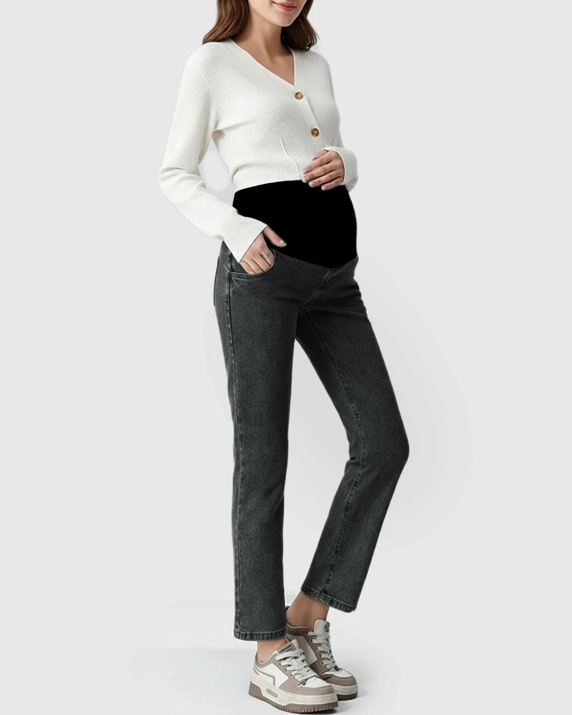 Pregnant model wearing dark wash straight-leg maternity jeans with a black belly band and white cardigan.