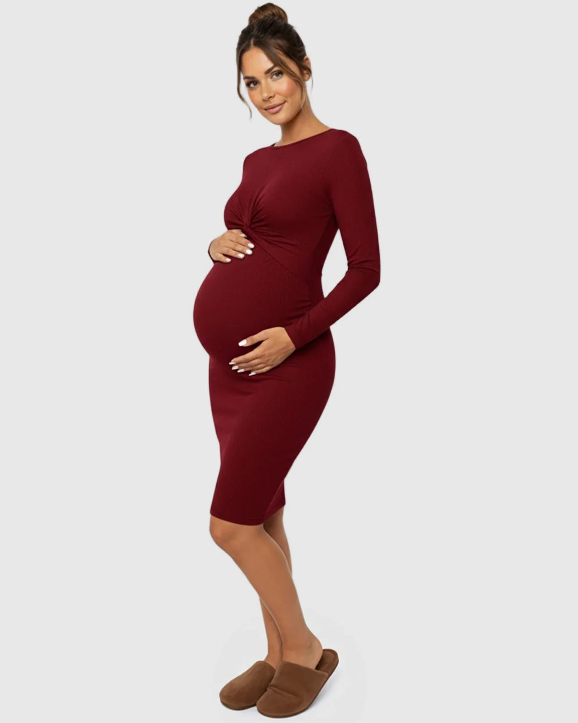 Maternity model in a long-sleeve, dark red ribbed bodycon dress with a twist-front detail, highlighting her bump.
