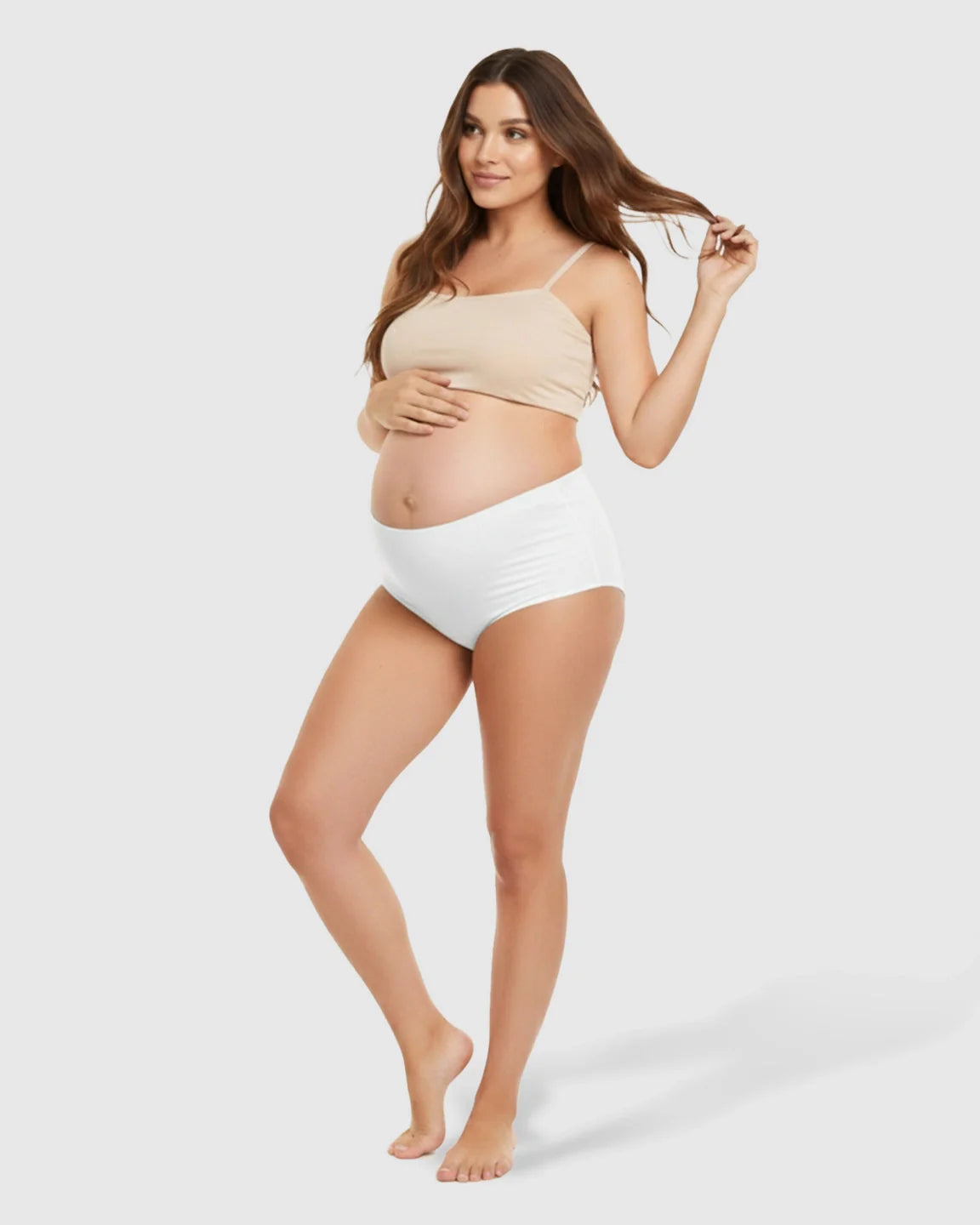 Pregnant woman modeling white seamless high-waist support maternity underwear and a nude bra.
