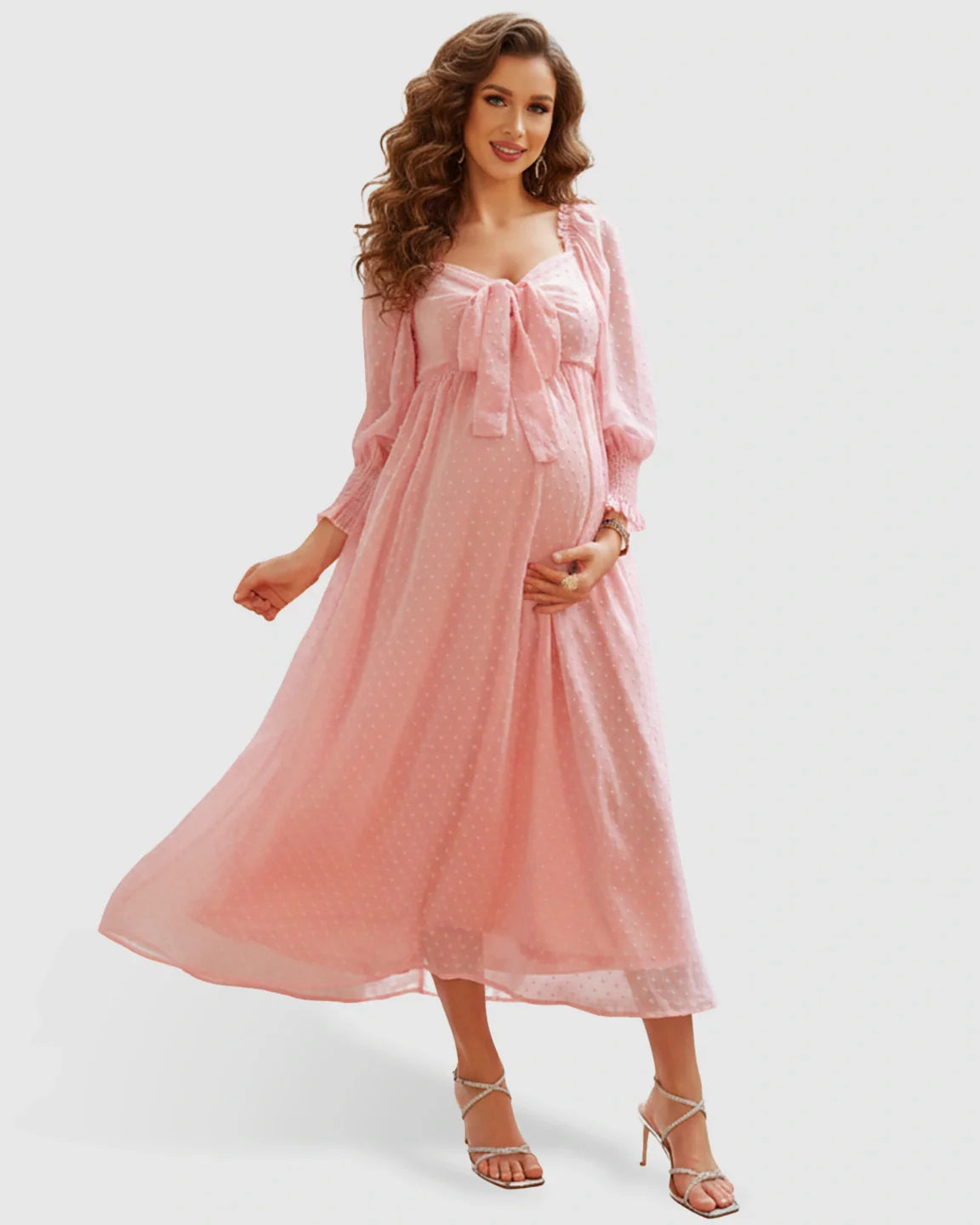 Smiling pregnant woman in a pink polka-dot chiffon maternity maxi dress with a square neckline and long sleeves.