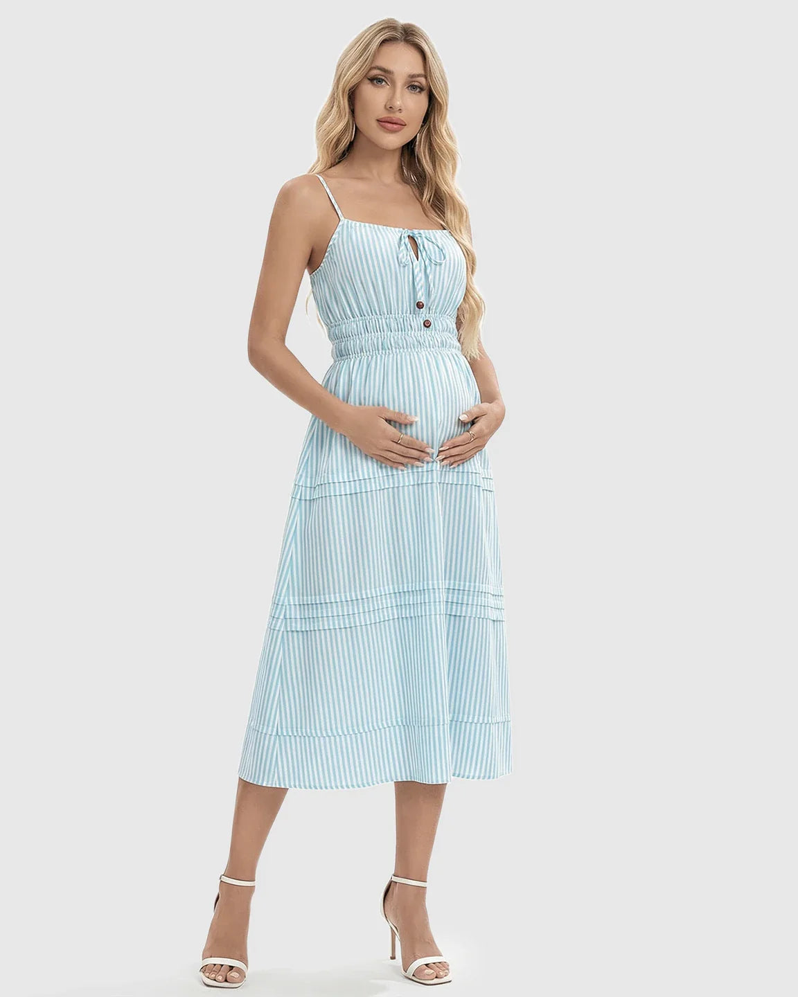 Pregnant woman in a blue and white striped smocked-waist A-line maternity midi dress with spaghetti straps.