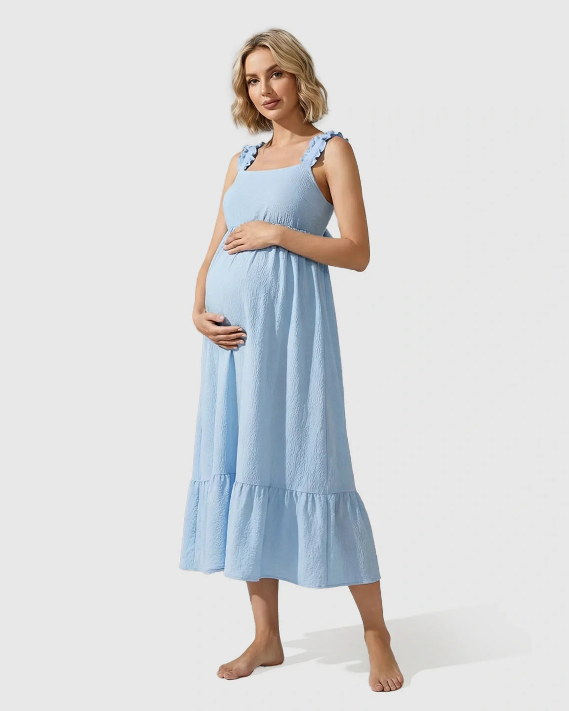 Pregnant woman in a light blue ruffled strap maternity maxi dress with a tiered skirt.