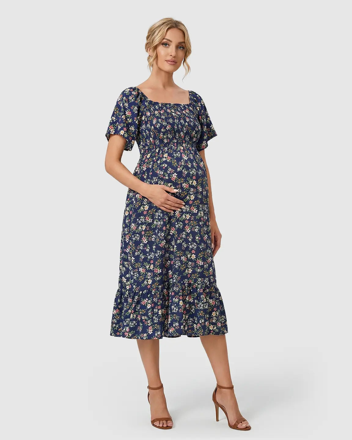 Maternity midi dress in navy floral print with flutter sleeves, smocked top, and tiered skirt.