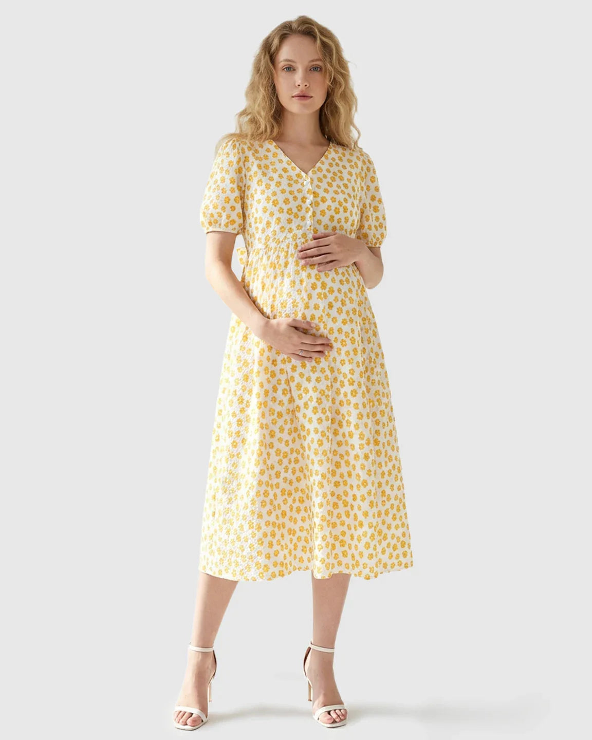 Maternity nursing dress: white midi with yellow floral print, V-neck, partial button-front, and puff sleeves.