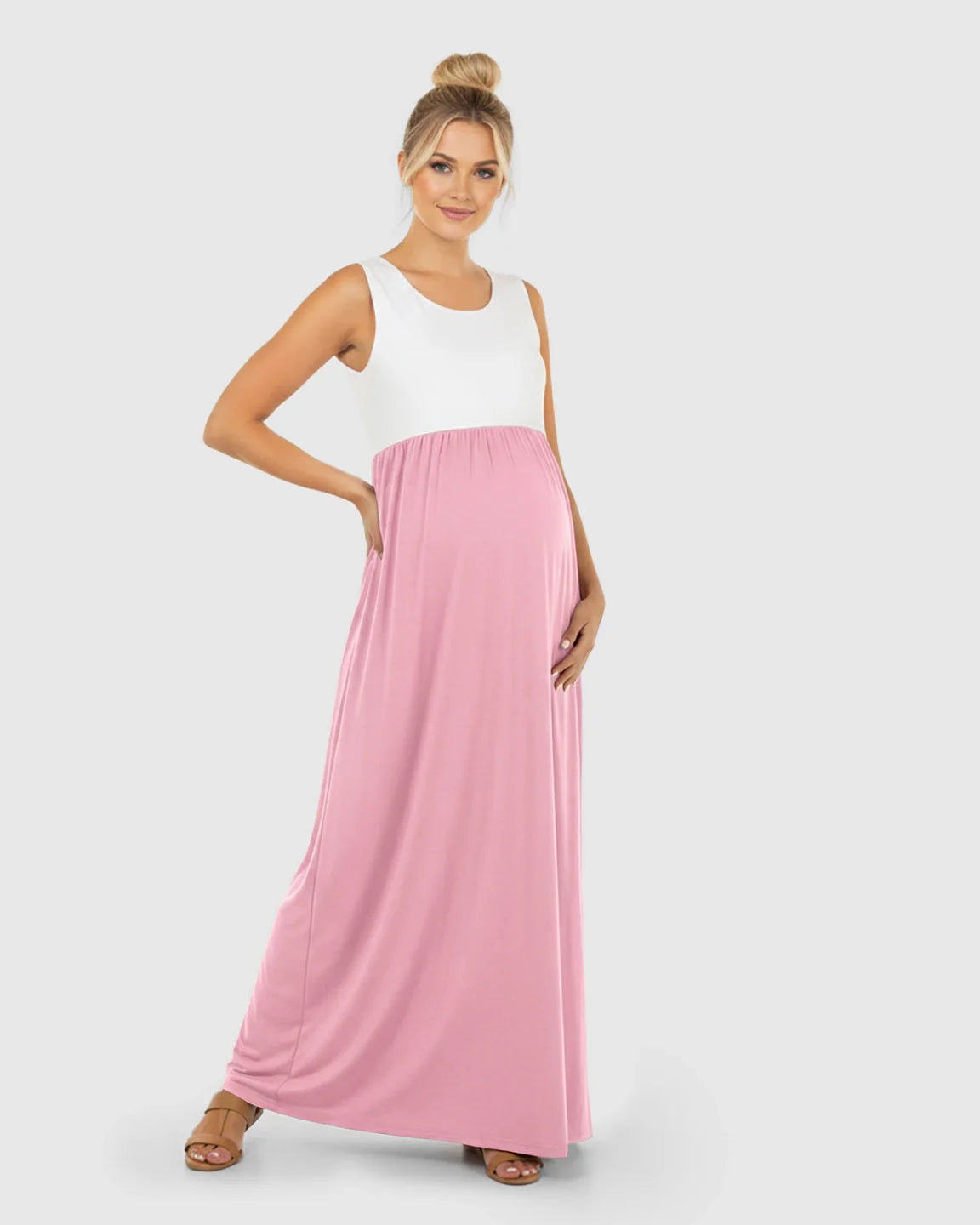 Smiling pregnant woman in a white and pink colorblock high-waisted maternity maxi dress with a flowing skirt.