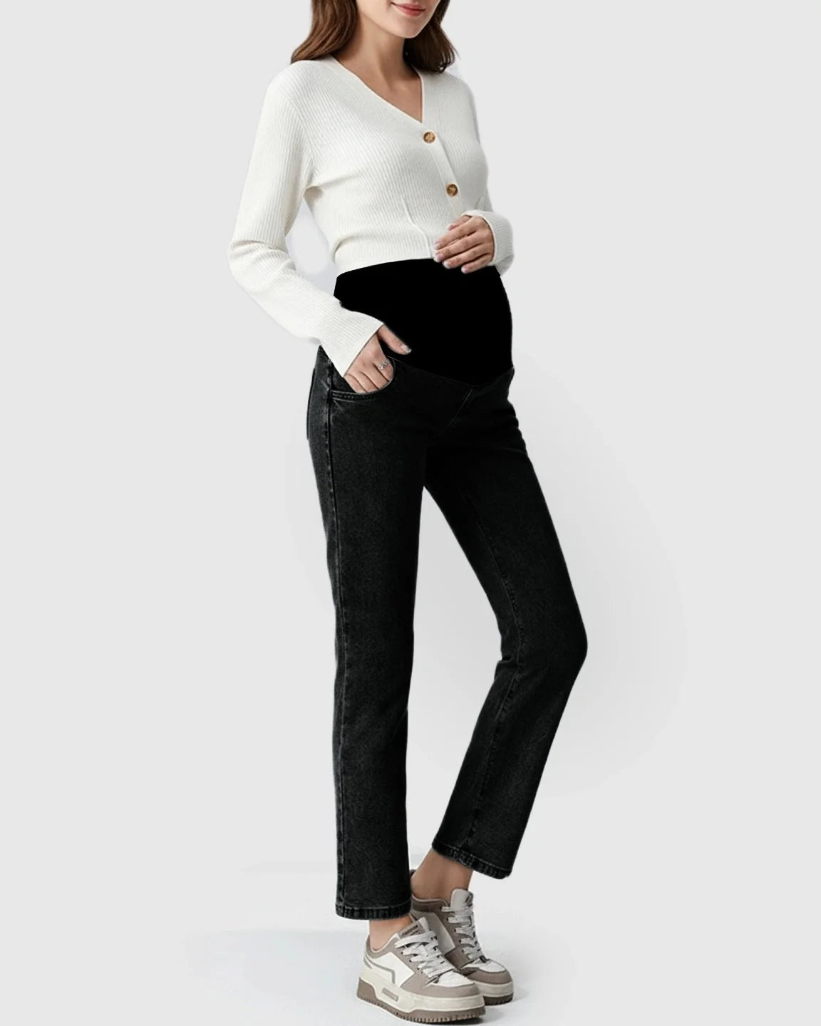 Woman in black stretch denim straight-leg maternity jeans with a supportive belly band and white cardigan.