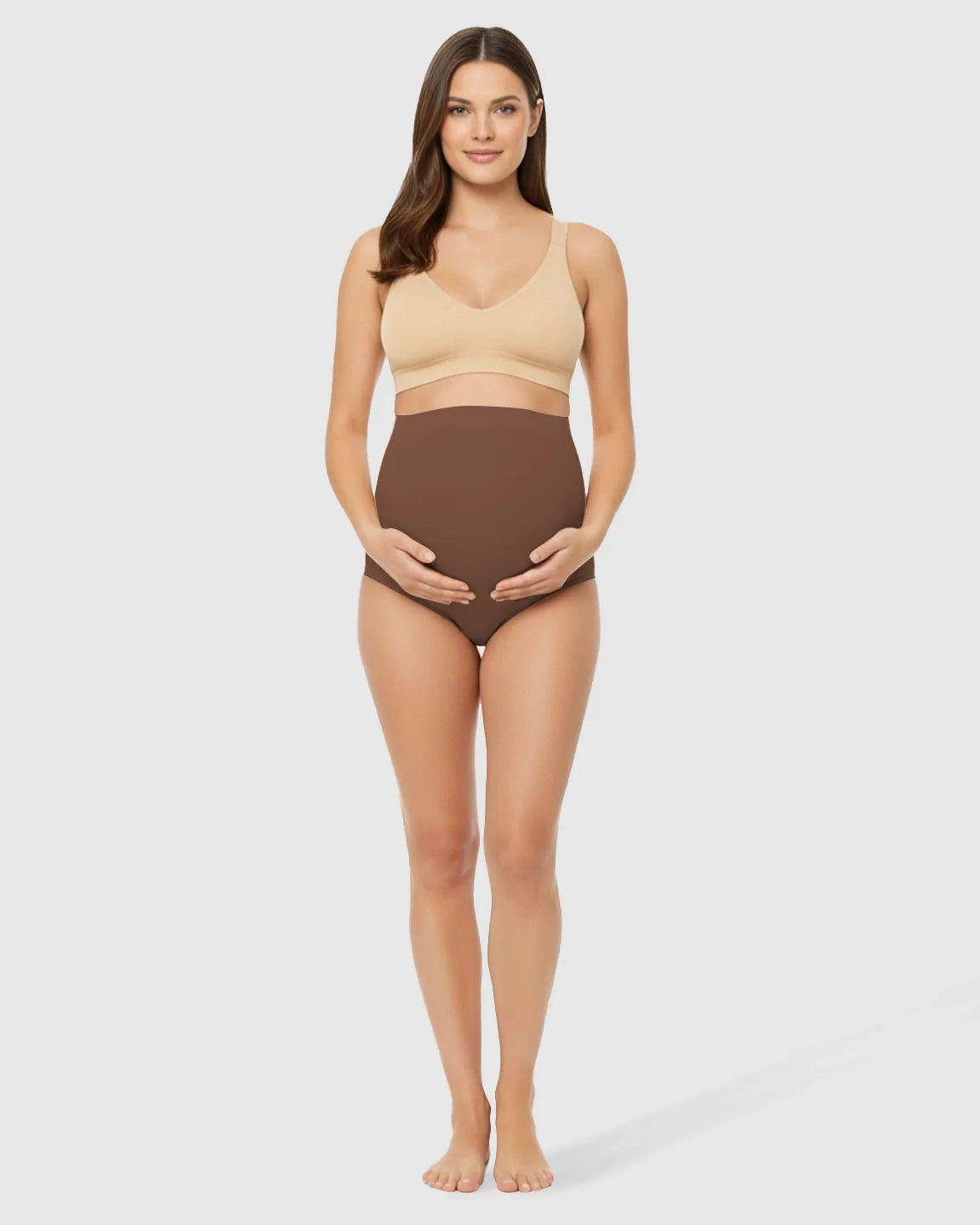 Smiling pregnant woman in brown high-waist seamless belly-support maternity underwear and a nude bra.