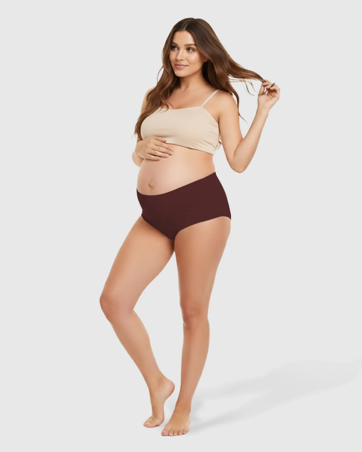Pregnant woman in seamless high-waist maroon maternity support underwear and a beige crop top.