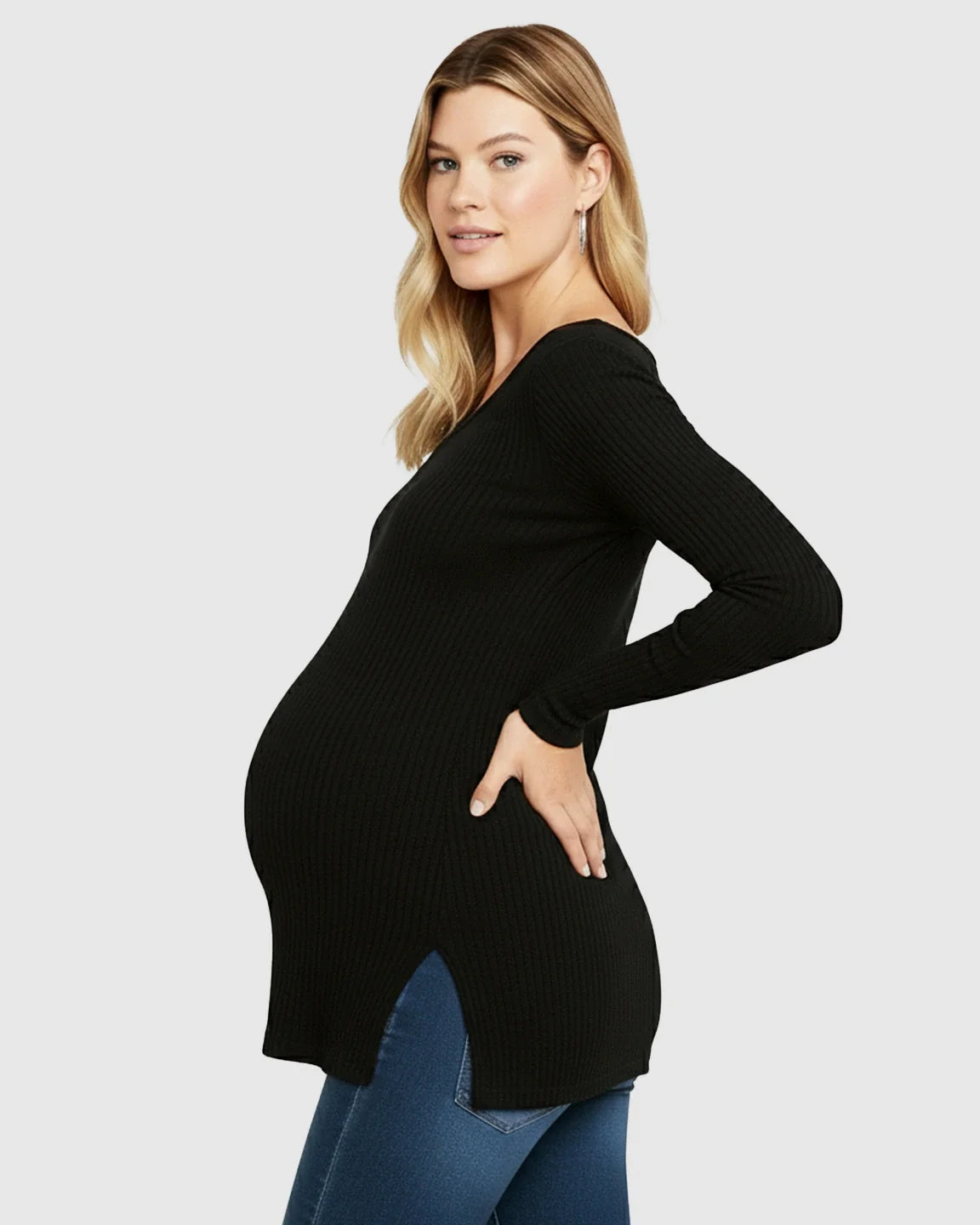 Pregnant woman in a black ribbed V-neck long sleeve maternity top with side slits, paired with jeans.