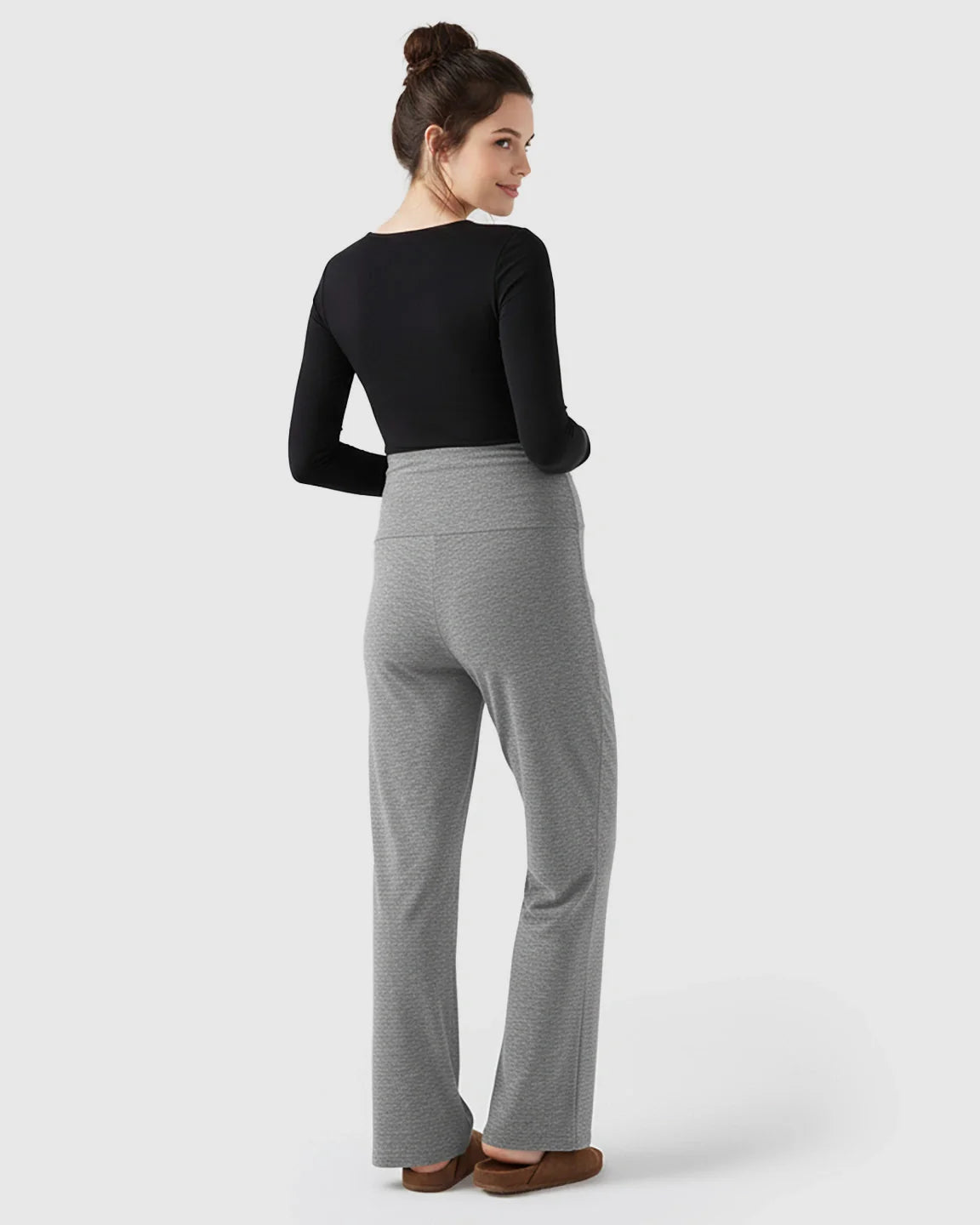 Woman in gray fleece relaxed maternity pants with over-belly waistband and wide-leg silhouette.