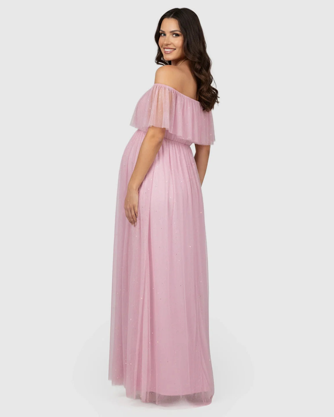 Smiling pregnant woman in a pink off-shoulder mesh slit maternity gown with a flutter neckline.