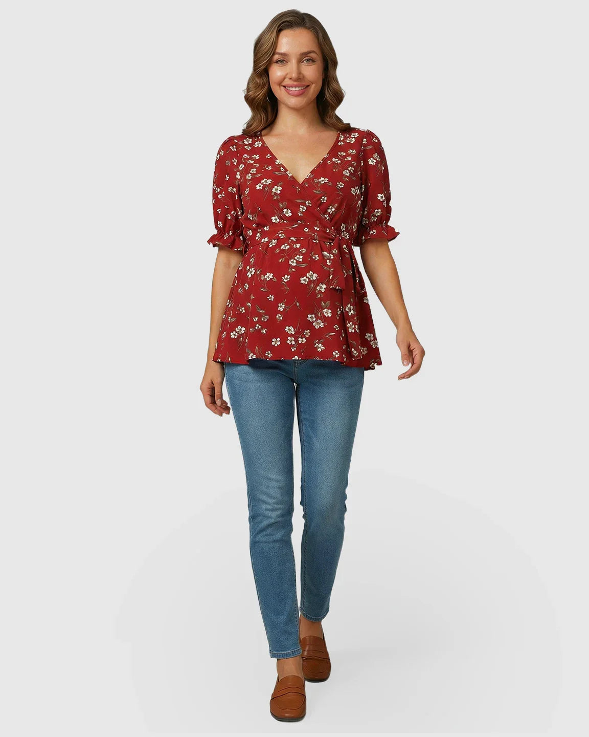 Red floral crossover V-neck maternity and nursing top with puff sleeves and tie waist, paired with jeans.