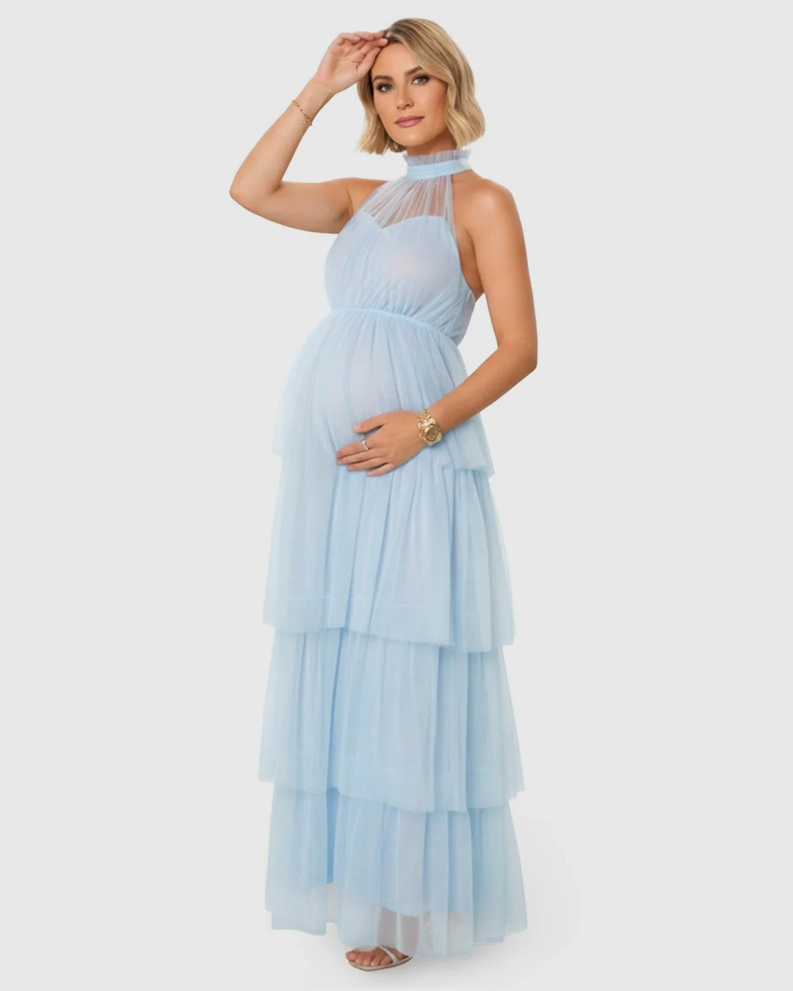 Pregnant woman in a light blue halter neck tiered mesh maternity gown.