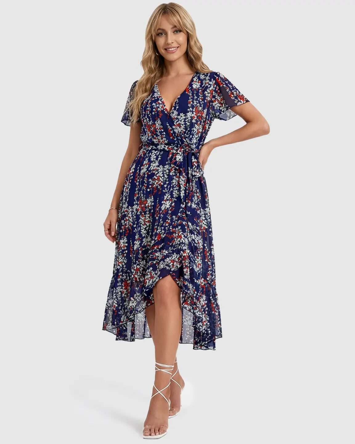 Smiling woman in a navy floral V-neck maternity midi dress with ruffled hem and tie waist.
