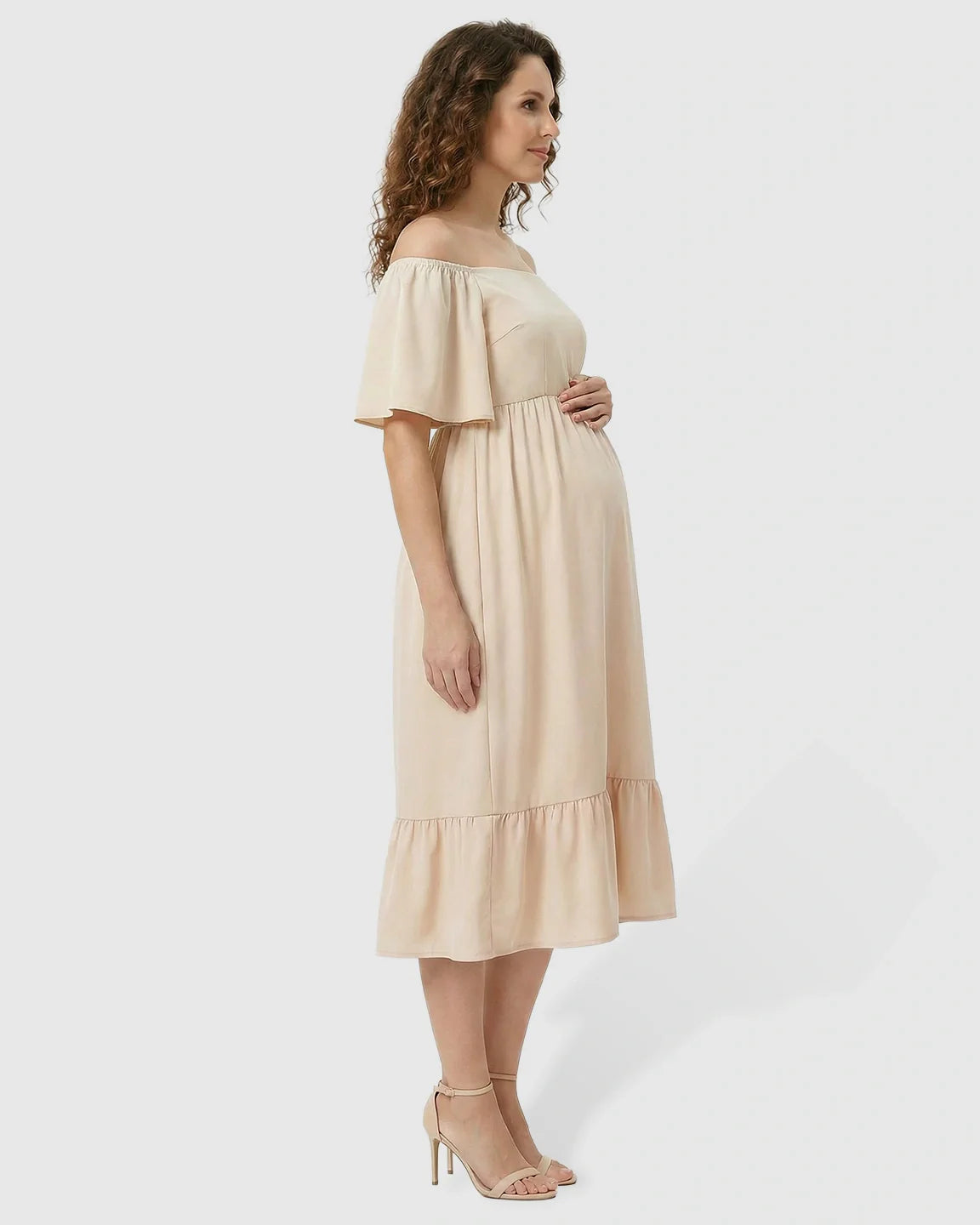 Maternity midi dress in light peach with off-shoulder smocked top, flutter sleeves, and tiered skirt.