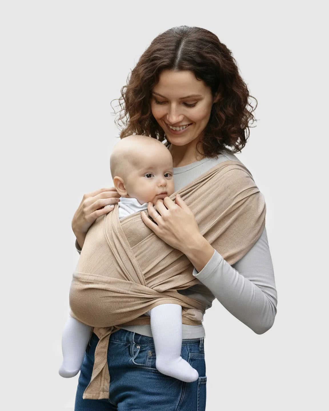 Smiling mom wearing a soft, beige adjustable wrap-around baby carrier with her infant.