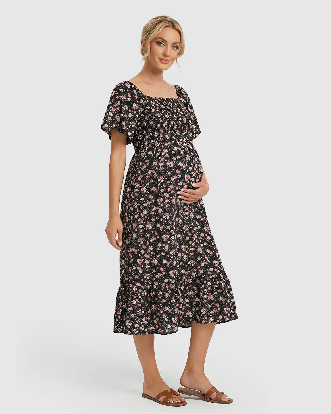 Pregnant woman in black floral flutter-sleeve smocked maternity midi dress with pink flowers.