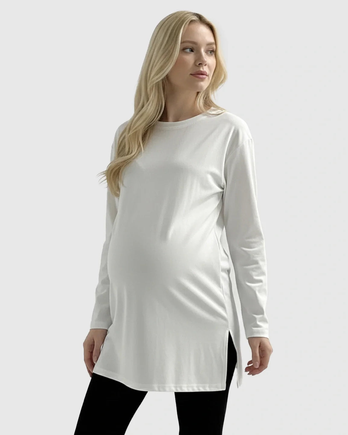 Blonde pregnant woman wearing a white long-sleeve soft cotton maternity top with side slits.