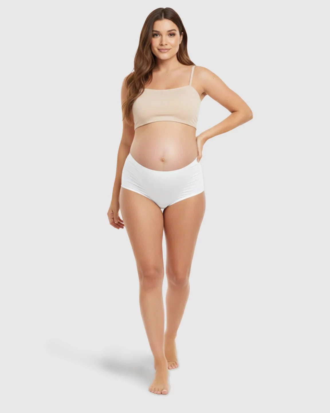 Pregnant woman modeling white seamless high-waist support maternity underwear and a nude bra.