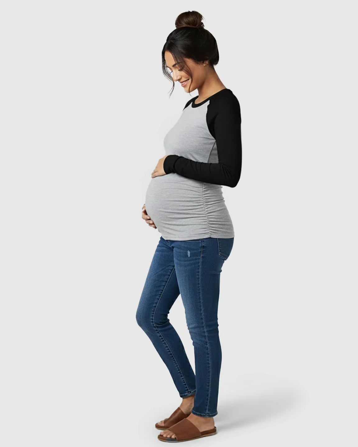 Pregnant woman in a gray and black raglan sleeve maternity top with side ruching and blue jeans.