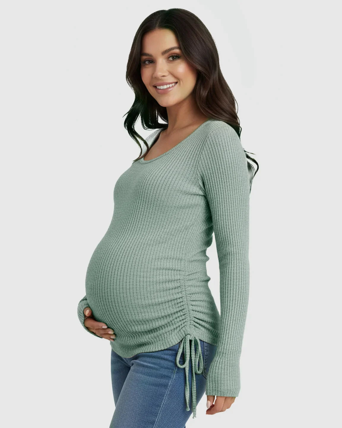 Smiling pregnant woman in a sage green ribbed long-sleeve maternity top with adjustable side drawstrings and U-neck.