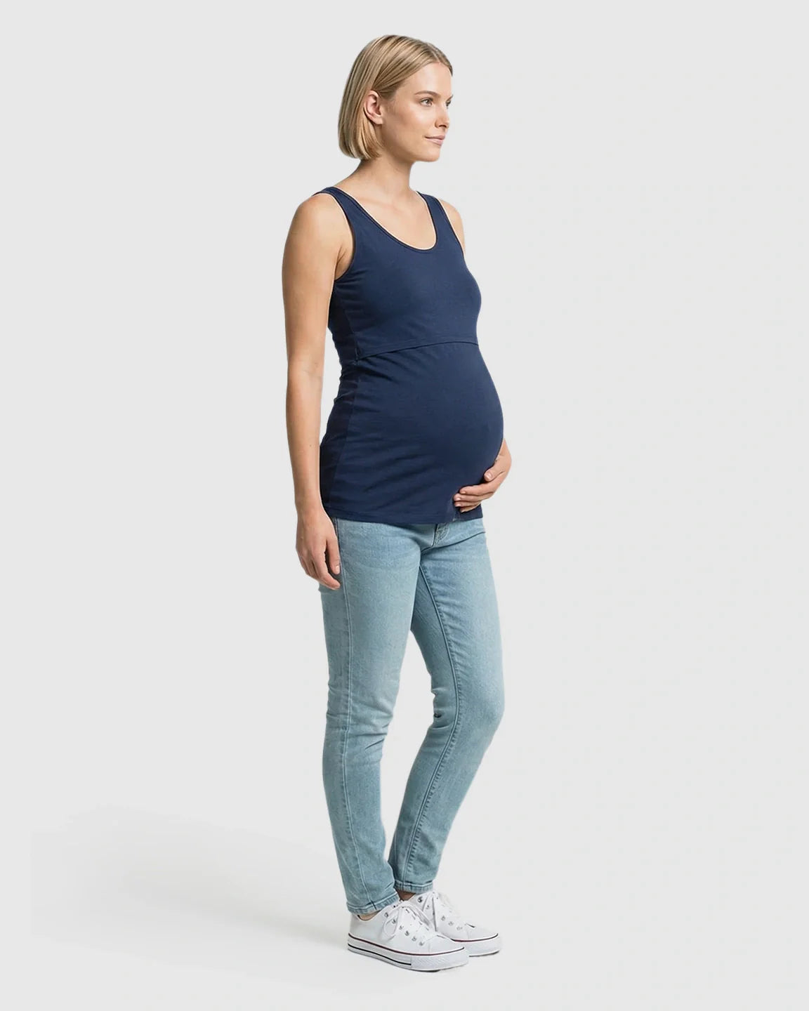 Pregnant woman in a navy stretch nursing-access maternity tank top and jeans.