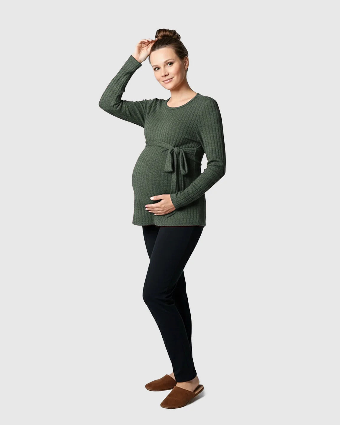 Smiling pregnant woman in a ribbed olive green tie-waist long sleeve maternity sweater and black pants.