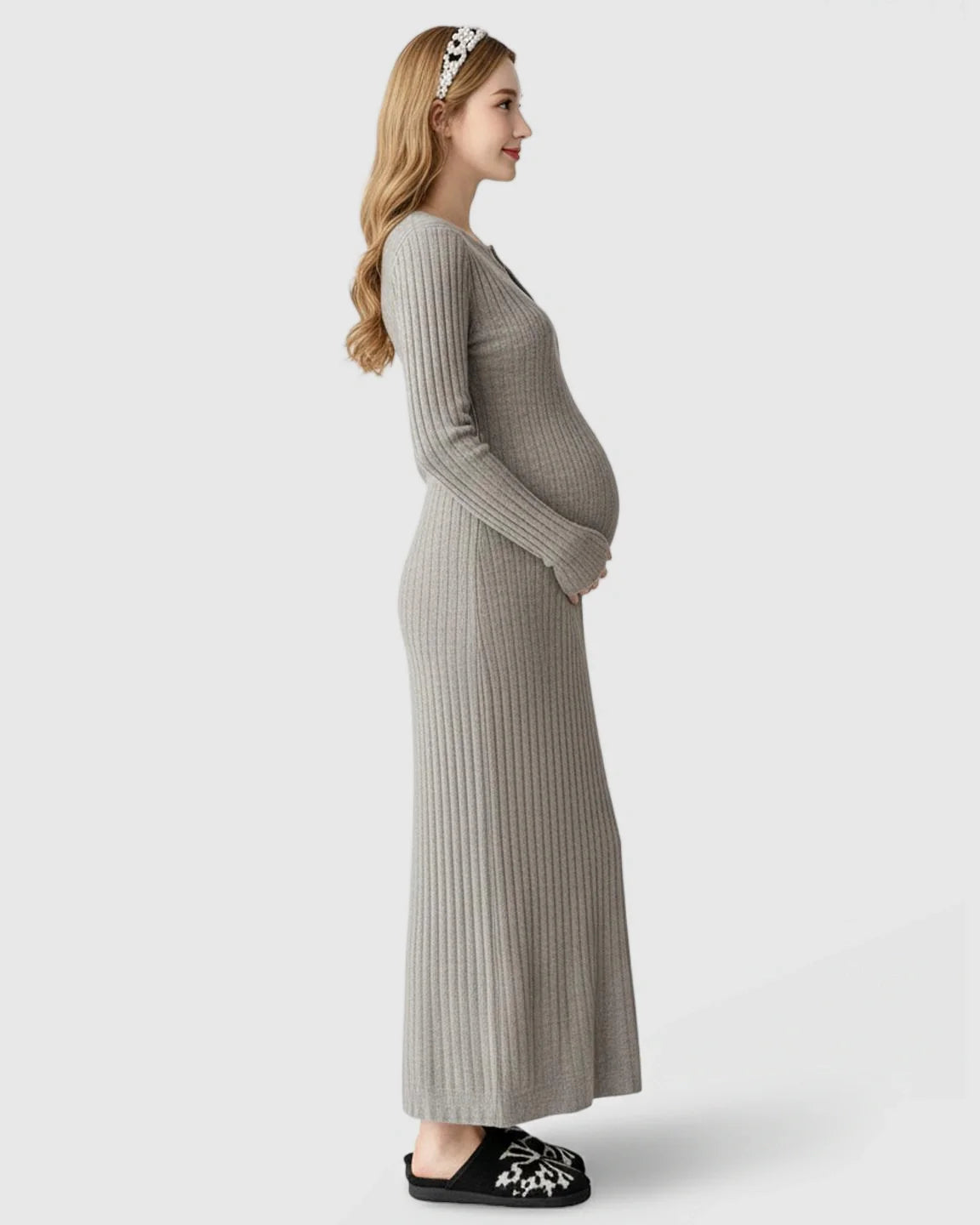 Pregnant woman in a gray ribbed knit A-line long sleeve maternity maxi dress, holding her bump.