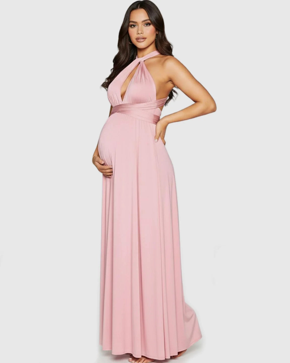 Pregnant woman in a pink tie-waist flowy maternity maxi dress with a halter neckline.
