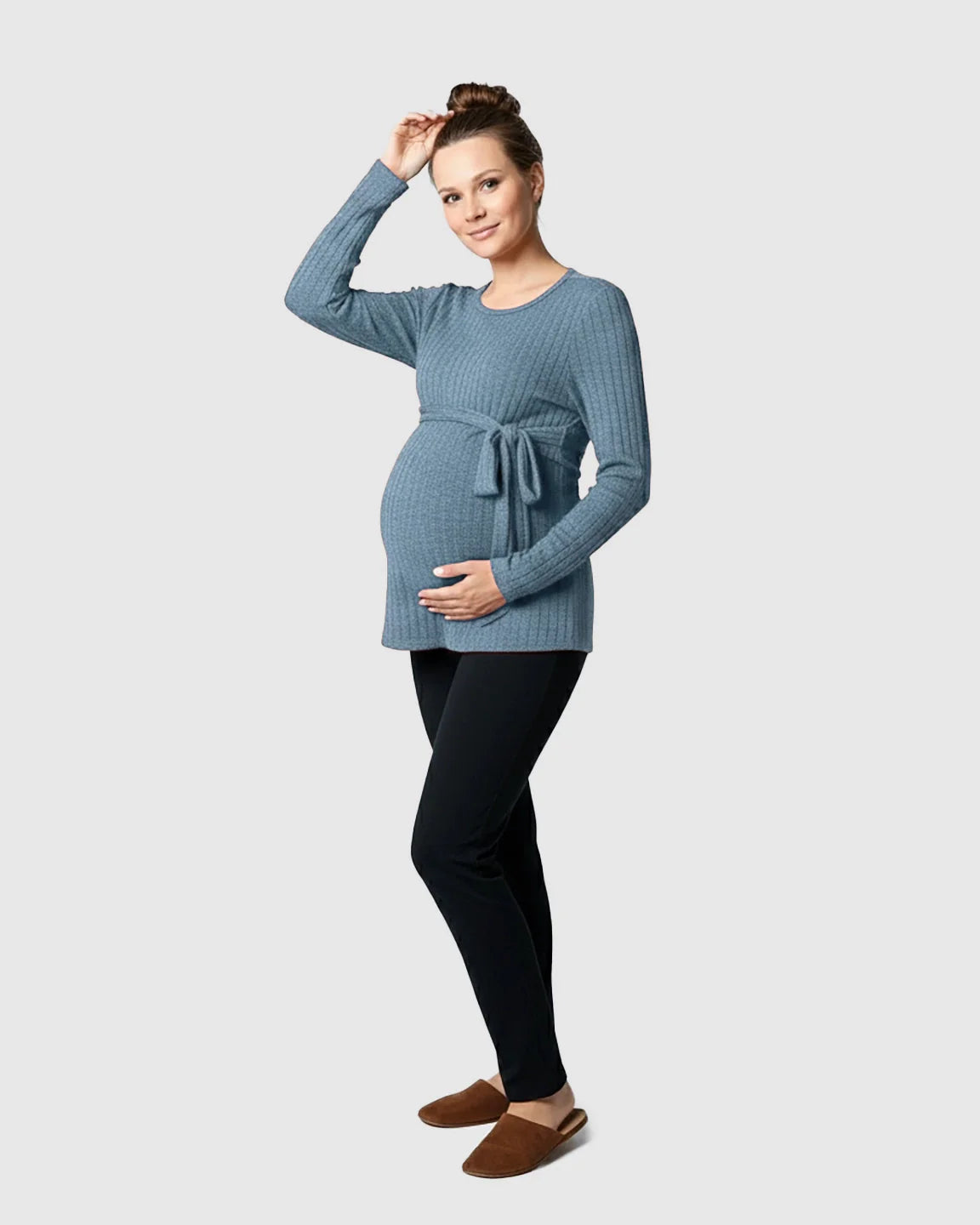 Pregnant woman in a blue ribbed tie-waist long sleeve maternity sweater and black pants.
