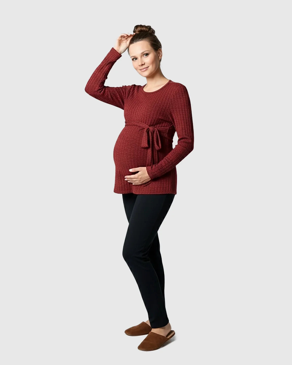 Pregnant woman in a ribbed, rust-colored tie-waist long sleeve maternity sweater and black pants.