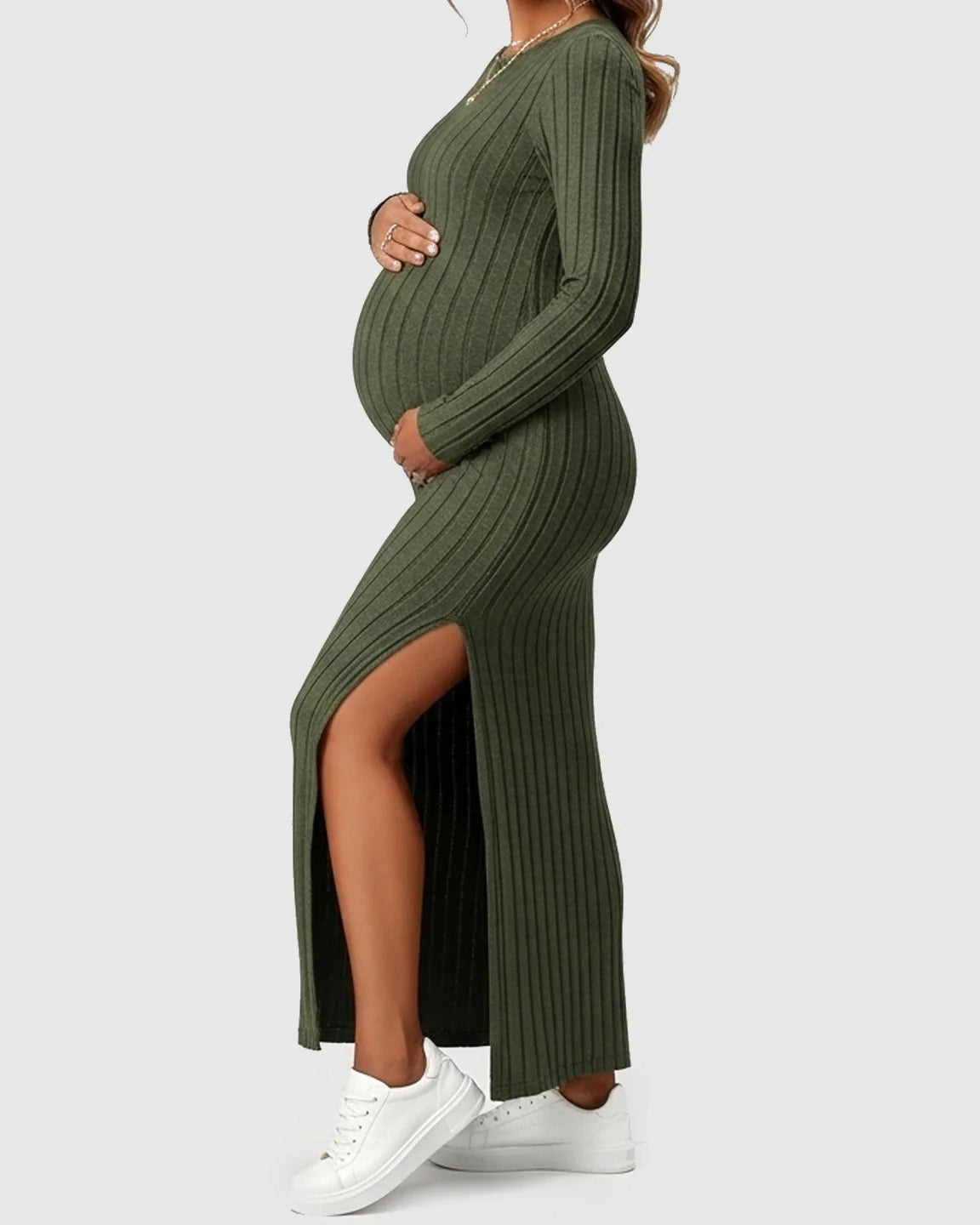 Pregnant woman in a green ribbed knit long-sleeve maxi dress with a high side slit.